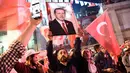 Seorang pria membawa poster Erdogan saat merayakan kemenangan dalam referendum di Istanbul, Turki (16/4). Pergantian sistem pemerintahan tersebut memungkinkan Erdogan memperoleh kekuasaan lebih luas dan masa jabatan lebih lama. (AFP Photo / Ozan Kose)