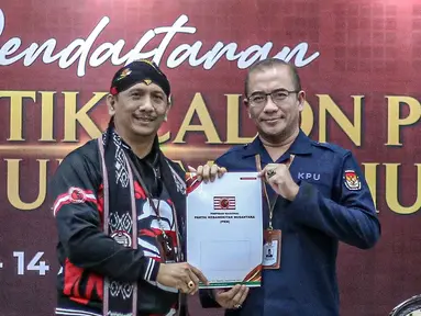 Ketua Komisi Pemilihan Umum (KPU) Hasyim Asy'ari (kanan) menerima berkas pendaftaran dari Ketua Umum Partai Kebangkitan Nusantara (PKN) I Gede Pasek Suardika (kiri) saat pendaftaran partai politik calon peserta pemilu tahun 2024 di Kantor KPU, Jakarta, Selasa (2/8/2022). Pada hari kedua pendaftaran, KPU menerima satu partai politik yang akan mendaftarkan diri sebagai calon peserta Pemilu 2024. (Liputan6.com/Faizal Fanani)