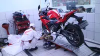 Mekanik bengkel Honda sedang melakukan service sepeda motor.