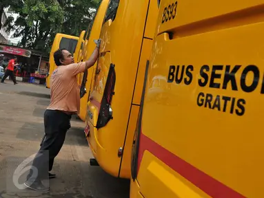 Pekerja membersihkan bus sekolah di Terminal Pasar Minggu, Jakarta, Senin (26/10). Gubernur DKI Basuki Tjahaja Purnama berencana menghapus keberadaan bus sekolah. Sebagai gantinya, pelajar akan digratiskan naik Transjakarta. (Liputan6.com/Gempur M Surya)