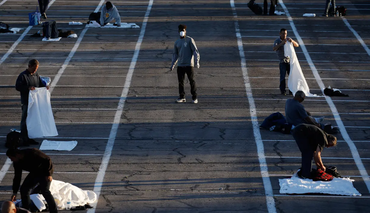 Tunawisma bersiap tidur di tempat-tempat yang ditandai dengan kotak-kotak untuk social distancing di lahan parkir di Las Vegas, Senin (30/3/2020). Lahan parkir itu menggantikan salah satu tempat penampungan lokal yang ditutup setelah seorang penghuni dinyatakan positif virus corona. (AP/John Locher)