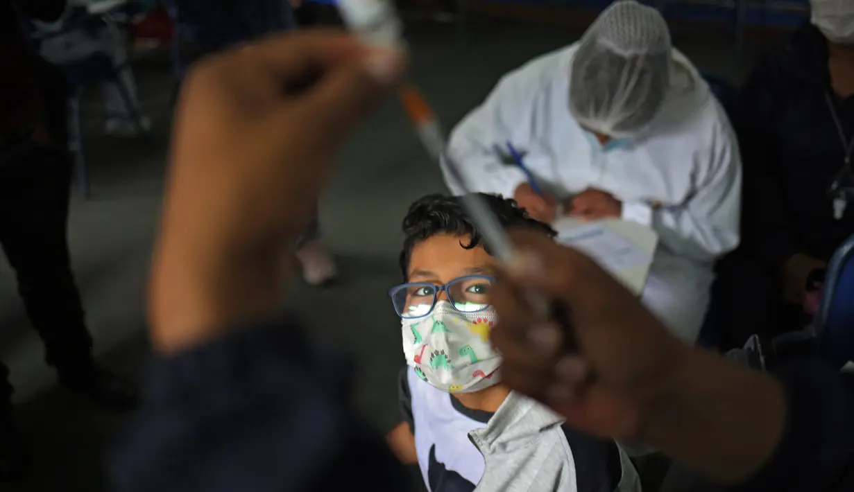Seorang anak menunggu untuk disuntik vaksin covid-19 Sinopharm di La Paz, Bolivia, Kamis (9/12/2021). Presiden Bolivia Luis Arce mengizinkan vaksinasi anak berusia antara 5 hingga 11 tahun untuk menekan laju peningkatan infeksi COVID-19 di negara itu. (LUIS GANDARILLAS / AFP)