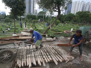 Pekerja menyelesaikan pembuatan saluran air di TPU Karet Bivak, Jakarta, Selasa (22/11). Saluran air tersebut berfungsi mencegah banjir yang sering menggenangi pemakaman setiap diguyur hujan. (Liputan6.com/Immanuel Antonius)