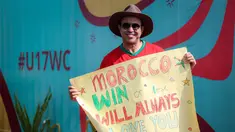 Suporter Maroko, Mohammad Aziz Mrabat berpose dengan membentangkan poster bertuliskan "Maroko, menang atau kalah aku tetap mencintaimu" menjelang laga kedua Grup A Piala Dunia U-17 2023 antara Timnas Maroko U-17 melawan Timnas Ekuador U-17 di Stadion Gelora Bung Tomo (GBT), Surabaya, Senin (14/11/2023). (Bola.com/Bagaskara Lazuardi)