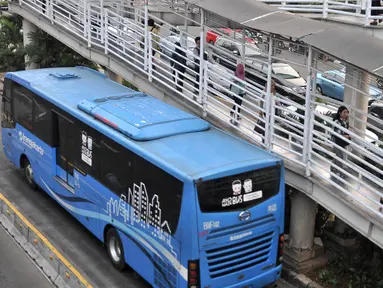 Calon penumpang melintasi jembatan saat hendak menggunakan bus Transjakarta di halte Tosari, Jakarta, Kamis (26/7). Gubernur DKI Jakarta Anies Baswedan mengklaim jumlah penumpang Transjakarta meningkat hingga 10 persen. (Merdeka.com/Iqbal S. Nugroho)