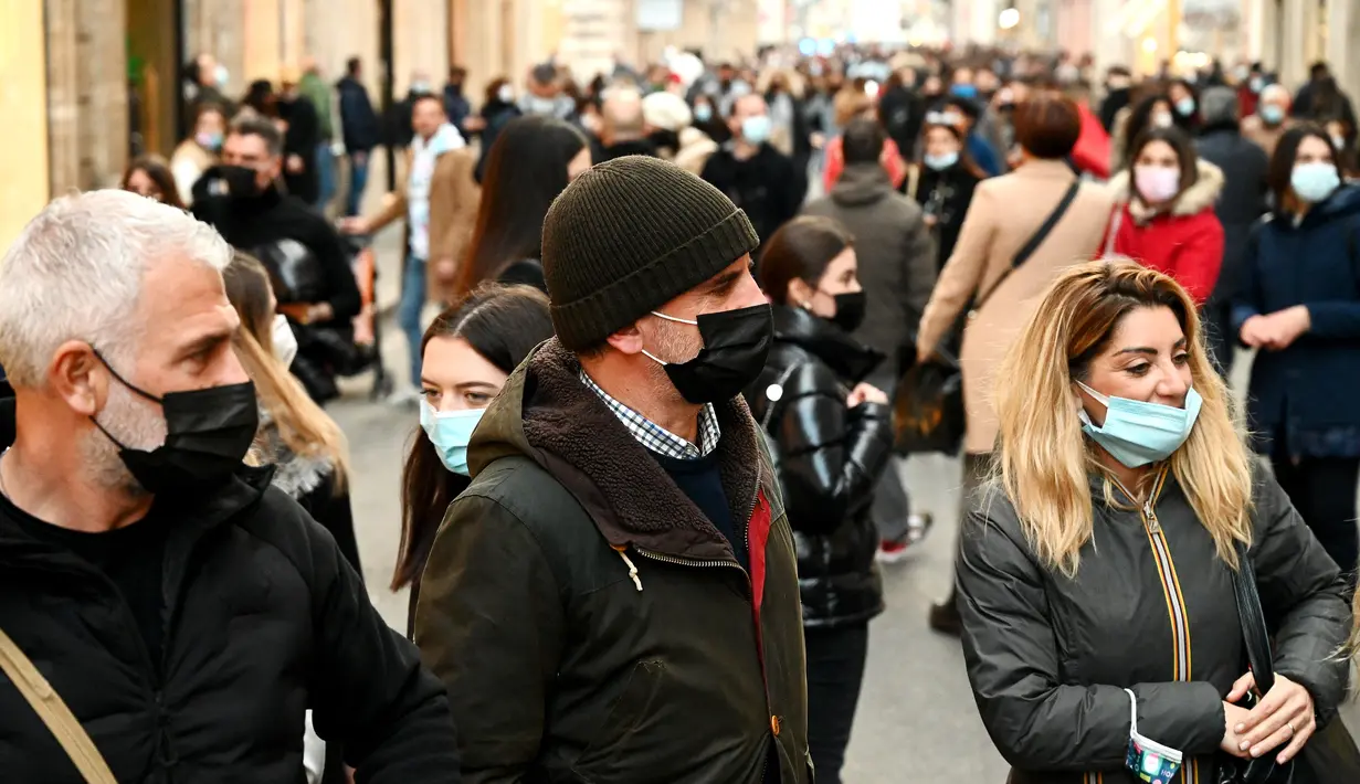 Orang-orang memakai masker di sepanjang jalan perbelanjaan mewah Via Condotti di pusat kota Roma, Italia, Minggu (5/12/2021). Kota Roma memberlakukan kewajiban penggunaan masker di ruang terbuka pusat kota dan area perbelanjaan sibuk lainnya hingga 31 Desember mendatang. (Vincenzo PINTO/AFP)