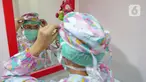 dr. J. Mila Hardiani C merapikan tutup kepala di ruang poli anak  di RSIA Tambak, Jakarta, Kamis (18/6/2020). Dokter menggunakan APD lengkap bertujuan untuk memberikan kenyamanan kepada anak-anak yang menjalani pemeriksaan juga guna mengantisipasi penularan COVID-19. (Liputan6.com/Herman Zakharia)