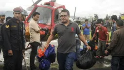 Petugas membawa barang milik korban tewas jatuhnya helikopter, di sebelah utara Ibu Kota Nepal, Kathmandu, Senin (8/8). Helikopter yang mengangkut enam warga lokal menuju Kathmandu itu hilang kontak 30 menit setelah lepas landas. (AFP PHOTO/BIKASH Karki)