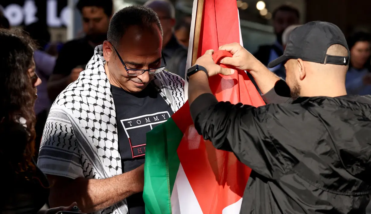 Para pengunjuk rasa menyiapkan bendera Palestina pada awal aksi protes terhadap aksi militer Israel di Gaza saat mereka berkumpul di Sydney pada 9 Oktober 2023. (David GRAY/AFP)