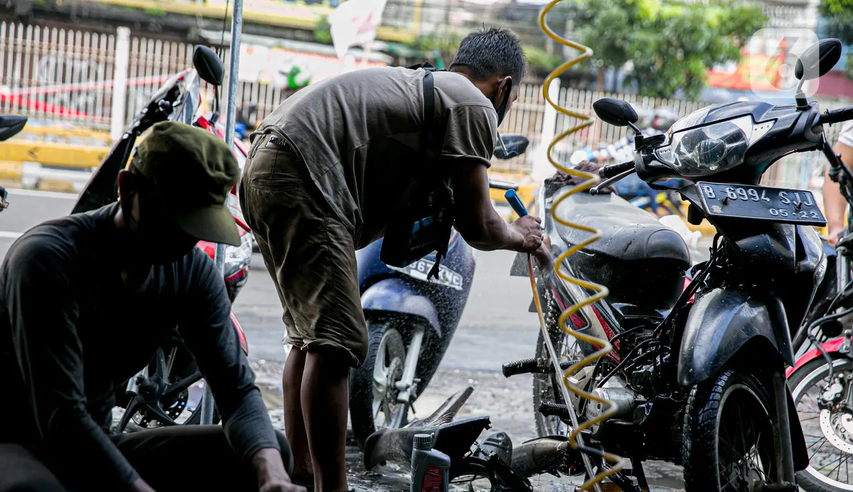 Montir membersihkan sepeda motor konsumen usai terendam banjir di kawasan Mampang, Jakarta, Minggu (21/2/2021). Banjir yang melanda Ibu Kota Jakarta pada Sabtu (20/2) menyebabkan banyak kendaraan warga mengalami kerusakan akibat terendam air. (Liputan6.com/Faizal Fanani)