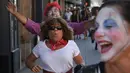 Seorang wanita berlari ketika dikejar badut dalam acara 'Running of the Clowns' di Pasadena, California pada 21 Oktober 2018. Lari dikejar kawanan badut ini merupakan parodi yang mengolok-olok lomba dikejar banteng di Pamplona, Spanyol. (Mark RALSTON/AFP)