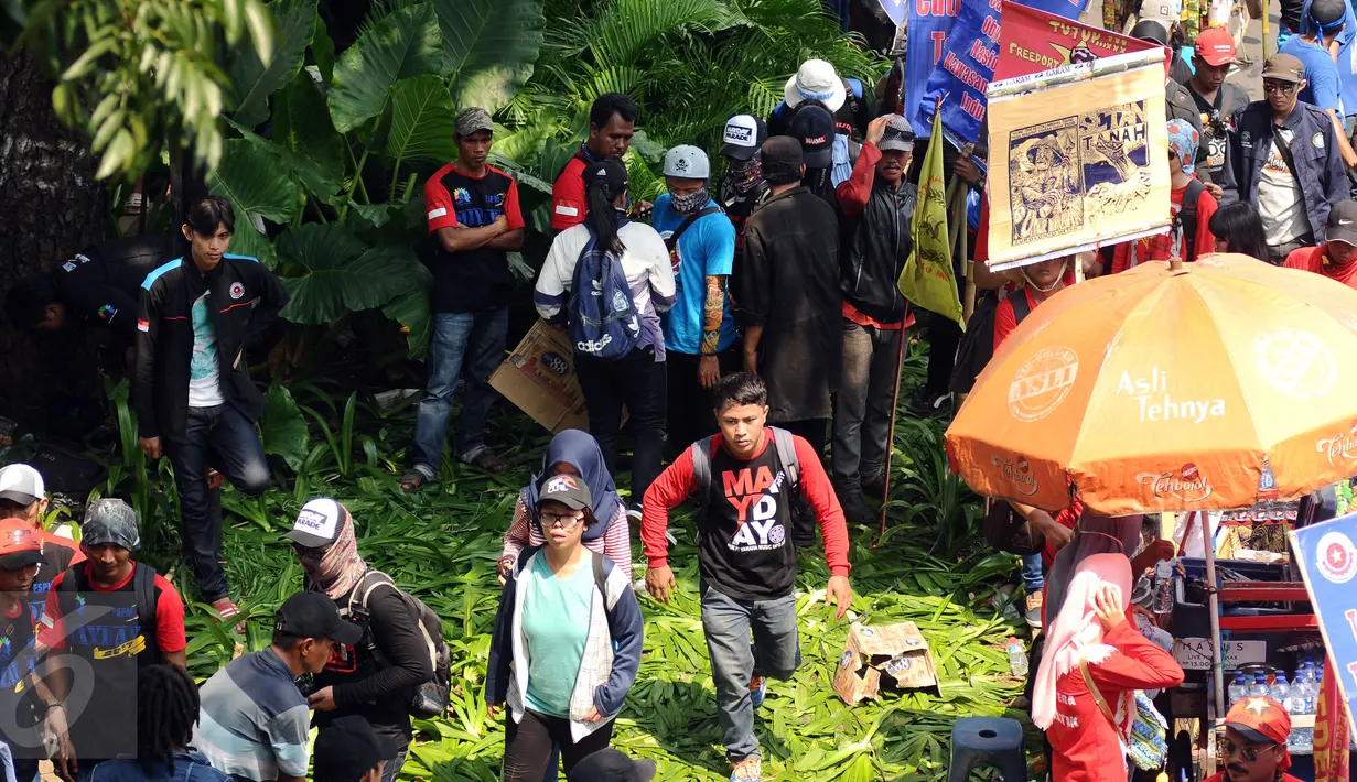 Massa buruh melintasi taman pembatas jalan di sekitar Kawasan Patung Patung Arjuna Wiwaha saat aksi perayaan hari Buruh Internasional 2017 di Jakarta, Senin (5/1). Ribuan massa buruh ikut turun ke jalan. (Liputan6.com/Helmi Fithriansyah)