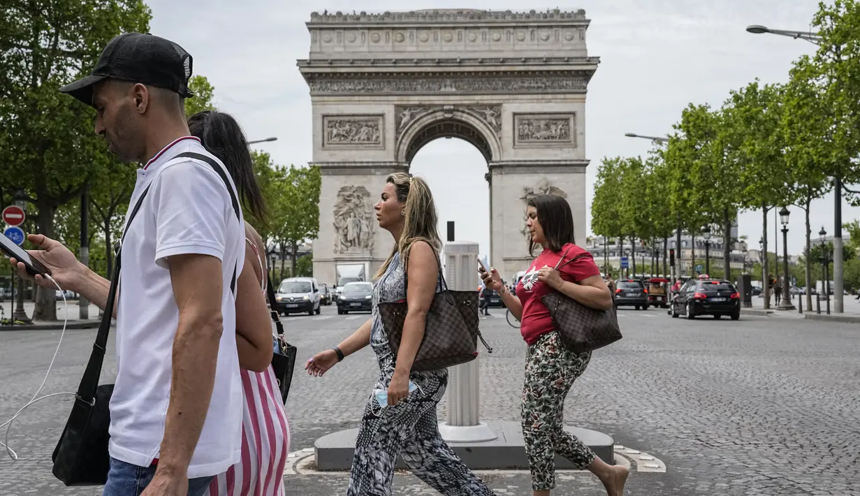 Orang-orang melintasi jalan Champs Elysees di Paris, Kamis (17/6/2021). Prancis mengumumkan melonggarkan aturan pembatasan COVID-19, mencabut aturan penggunaan masker di luar ruangan dan menghentikan jam malam mulai pekan ini setelah diberlakukan selama delapan bulan terakhir (AP Photo/Michel Euler)