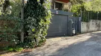 Pintu garasi rumah seorang diplomat senior Italia di pinggiran kota Athena, Yunani ditutup menyusul serangan yang menghancurkan sebuah mobil dan merusak yang kedua. (Lefteris Pitarakis/AP)