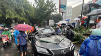 Sebuah mobil mewah bermerek Lexus tertimpa pohon tumbang di Jalan Metro Pondok Indah, Jakarta, Minggu (26/10/2025). (merdeka.com/Arie Basuki)