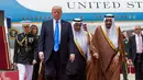 Donald Trump disambut Raja Salman saat tiba di Bandara Internasional Raja Khalid di Riyadh (20/5). Kunjungan ini akan membicarakan perjanjian politik dan perdagangan serta dukungan atas perang melawan para militan. (AFP/Saudi Royal Palace/Bandar Al-Jalou)