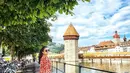 Mayangsari menyusuri jalan di Lucerne, Swiss, di mana banyak sepeda diparkir dan dari seberang kali terlihat gedung tua. (Foto: Instagram/@mayangsari_official)