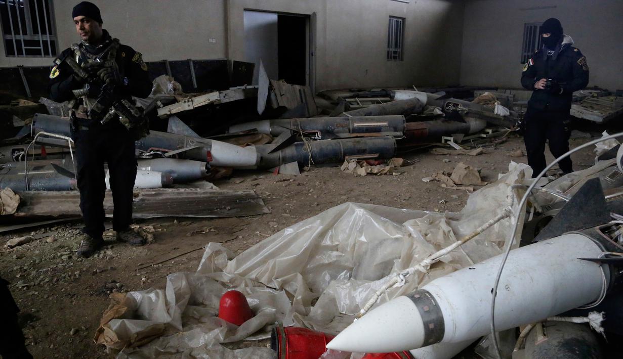Pasukan khusus Irak berjaga dekat rudal yang ditemukan di sebuah gudang senjata milik ISIS di sisi timur Mosul, Sabtu (28/1). Gudang itu berisi puluhan roket peninggalan mantan diktator Irak Saddam Hussein dan gas mustard. (AP Photo/Khalid Mohammed)