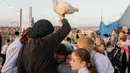 Seorang wanita Yahudi Ultra-Ortodoks mengayunkan ayam di atas kepala anak-anak selama ritual Kaparot di Beit Shemesh, Israel, Minggu (6/10/2019). Praktik ini dilakukan dengan mengayunkan ayam memutari kepala sebanyak tiga kali dengan iringan doa-doa. (MENAHEM KAHANA / AFP)
