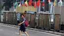 Pejalan kaki menyeberang dekat bendera negara peserta Asian Games 2018 yang diikat di tiang bambu di pagar pembatas Jalan Pluit Selatan Raya, Jakarta, Kamis (19/7). Pemasangan itu inisiatif warga dalam memeriahkan Asian Games. (Liputan6.com/Arya Manggala)