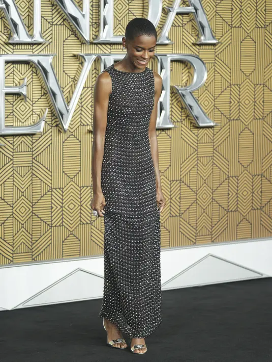 Letitia Wright berpose saat tiba menghadiri pemutaran perdana film 'Black Panther: Wakanda Forever' di London, Kamis, 3 November 2022. Rok slinky-nya menampilkan desain highneck dan tanpa lengan, dan rok yang mengalir. (Photo by Scott Garfitt/Invision/AP)