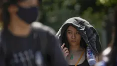 Seorang wanita menggunakan jaketnya untuk melindungi dari sinar matahari berjalan di sepanjang jalan saat ibu kota dilanda gelombang panas di Beijing, Senin, 5 Juni 2023. (AP Photo/Andy Wong)