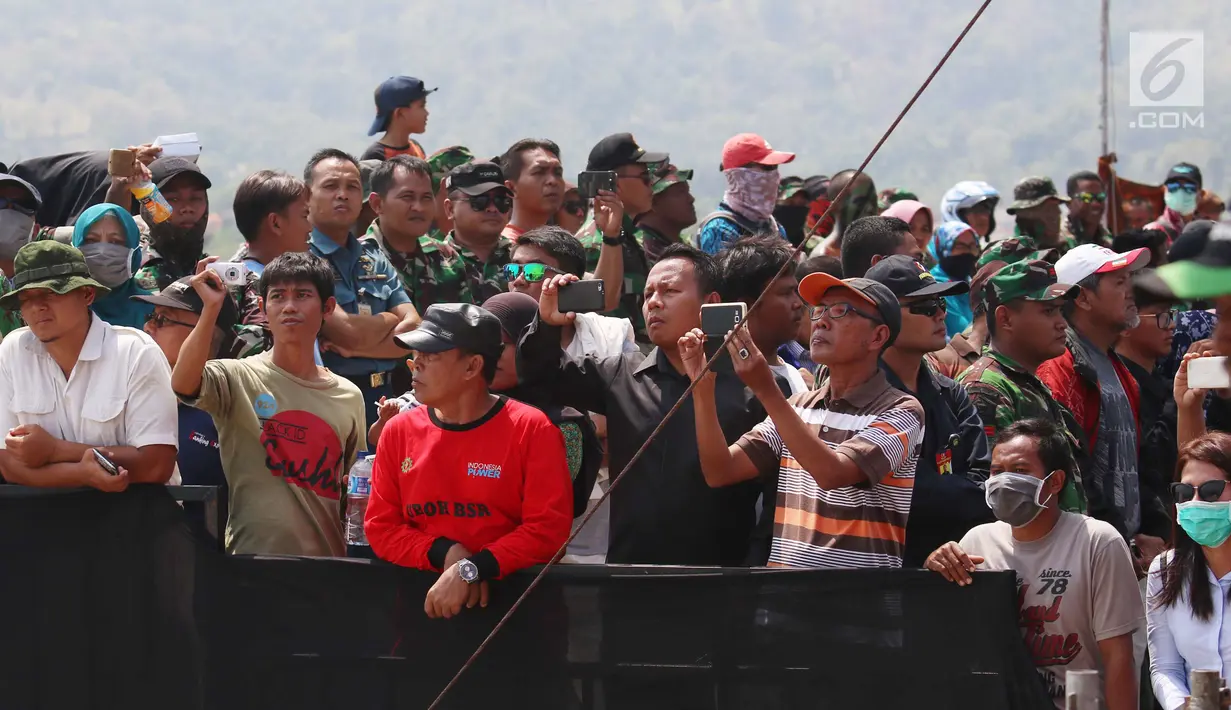 Masyarakat mengambil gambar saat menonton atraksi militer TNI dalam geladi resik HUT TNI ke-72 di Cilegon, Banten, Selasa (3/10). Geladi resik tersebut untuk memperingati HUT TNI ke-72 yang dilaksanakan tanggal 5 Oktober. (Liputan6.com/Angga Yuniar)