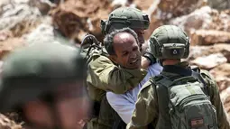Tentara Israel mengamankan seorang pengunjuk rasa Palestina yang memprotes pembukaan lahan untuk permukiman Israel di dekat Desa Shoufah, wilayah Tepi Barat (20/8/2020). (AFP/JAAFAR ASHTIYEH)