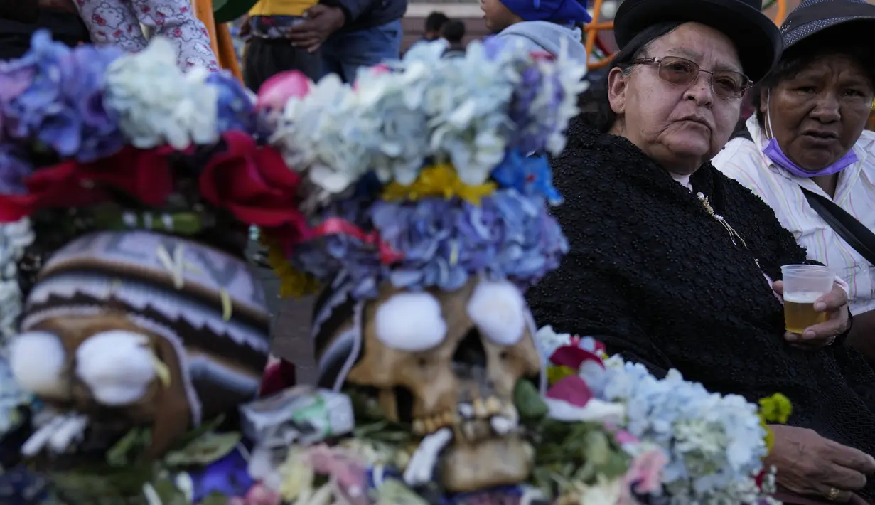Para wanita duduk di samping tengkorak yang dihias di luar pemakaman umum selama festival tahunan "Natitas" di La Paz, Bolivia, Senin (8/11/2021). Warga ramai-ramai menghias tengkorak leluhur mereka dengan berbagai dekorasi mulai dari bunga, topi, kacamata dan hiasan lainnya. (AP Photo/Juan Karita)