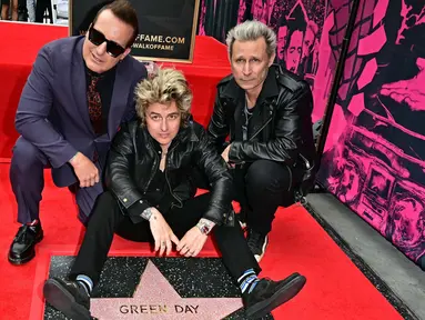 Personel grup band punk rock Green Day, Billie Joe Armstrong (tengah), Mike Dirnt (kanan), dan Tre Cool berpose dengan bintang mereka yang baru saja diresmikan di Hollywood Walk of Fame dalam sebuah upacara di Hollywood, California, Amerika Serikat pada 1 Mei 2025. (Frederic J. Brown/AFP)