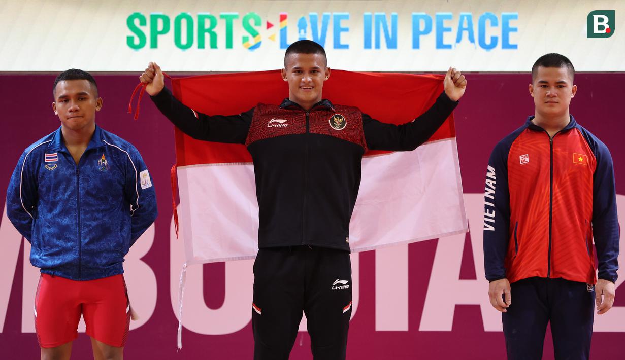 Atlet Indonesia, Rizki Juniansyah (tengah), setelah berhasil memenangkan laga pada cabang angkat besi 73 Kg putra SEA Games 2023 di Phnom Penh, Kamboja, Minggu (14/5/2022). Rizki berhasil mengalahkan Ky Su Bui (kanan) dari Vietnam diposisi kedua dan Anucha Doungsri dari Thailand yang meraih posisi ketiga. (Bola.com/Abdul Aziz)
