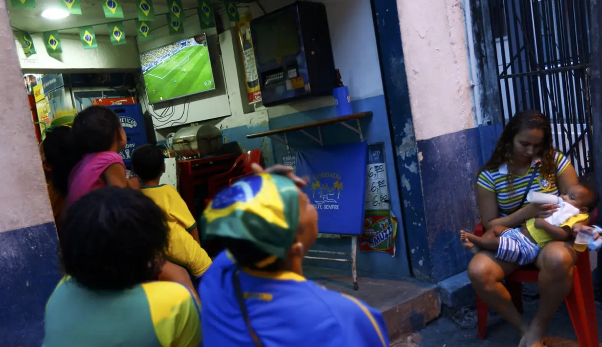 Laga Brasil kontra Kamerun di penyisihan Piala Dunia 2014 Grup A menyita perhatian warga, termasuk yang tinggal di kawasan kumuh Pavao-Pavaozinho, Rio de Janeiro, (23/6/2014). (REUTERS/Ricardo Moraes) 