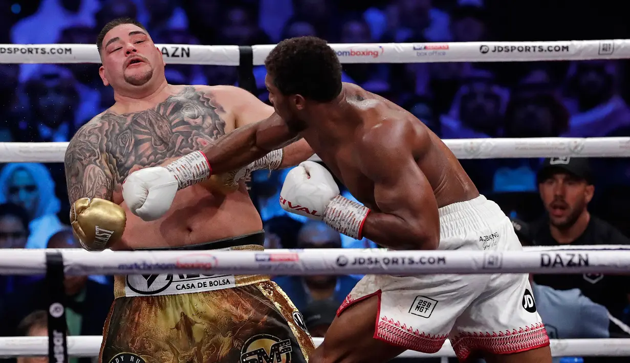 Petinju Andy Ruiz Jr (kiri) menghindar saat Anthony Joshua (kanan) melepaskan pukulan ke arahnya dalam kejuaraan tinju kelas berat dunia di Diriyah Arena, Riyadh, Arab Saudi, Minggu (8/12/2019). Anthony Joshua menang angka mutlak atas Andy Ruiz Jr. (AP Photo/Hassan Ammar)