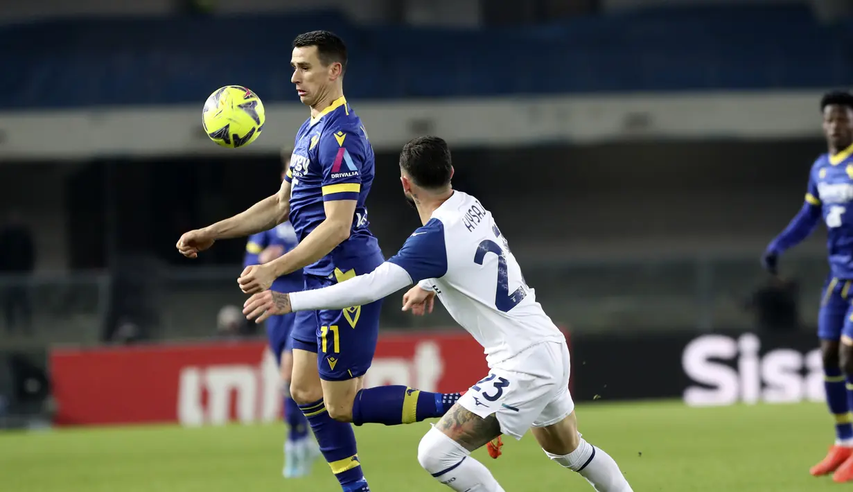 Bek Lazio Elseid Hysaj berebut bola dengan penyerang Hellas Verona Kevin Lasagna dalam laga pekan ke-21 Serie A di Stadio Marc'Antonio Bentegodi, Selasa (7/02/2023). Bermain di kandang Verona, kedua tima bermain imbang dengan skor 1-1. (Paola Garbuio/LaPresse via AP)