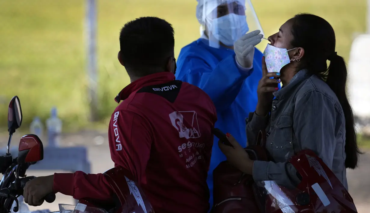 Seorang petugas kesehatan mengambil sampel usap hidung dari seorang pria untuk tes COVID secara gratis di tempat pengujian drive-thru di arena pacuan kuda di Capiata, Paraguay, Selasa (11/1/2022).  (AP Photo/Jorge Saenz)