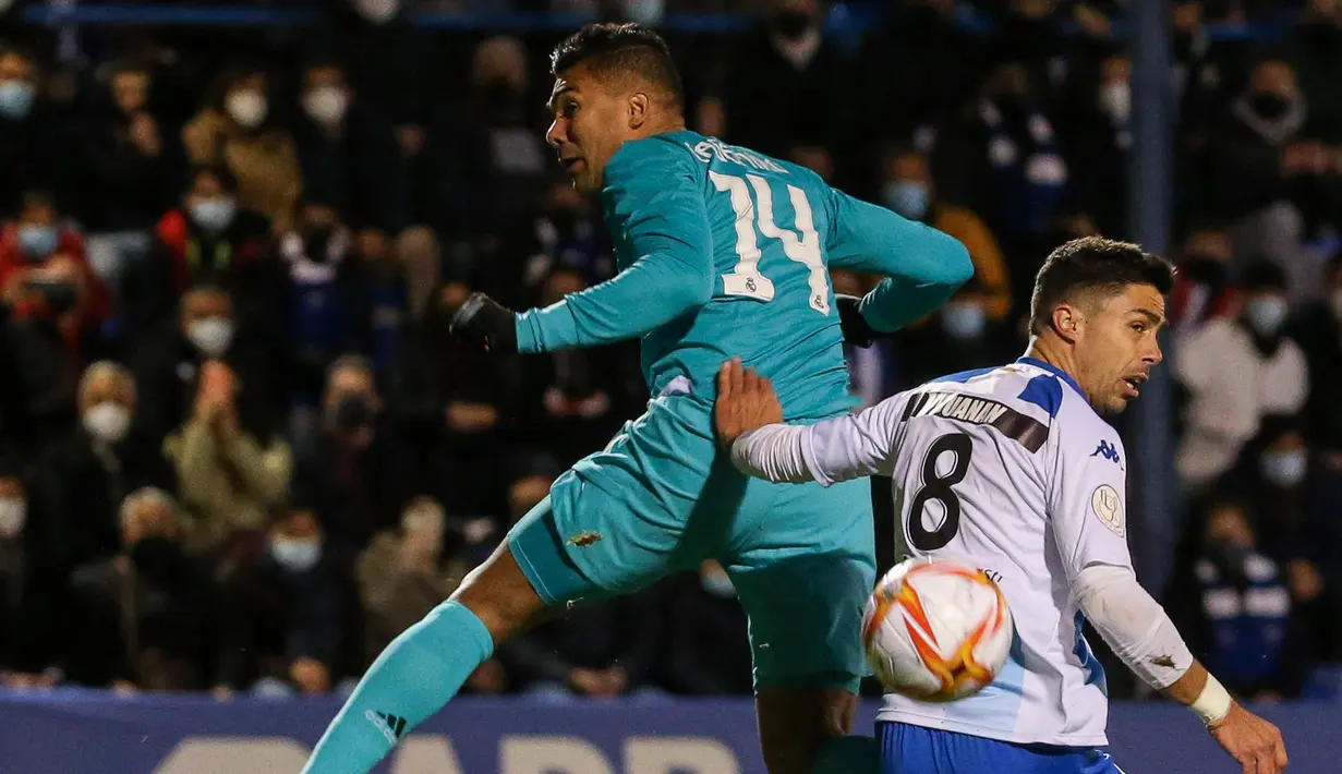 Gelandang Real Madrid Casemiro (kiri) berebut bola dengan gelandang Alcoyano, Juanan pada babak 32 besar Copa del Rey di Stadion El Callao, Alcoy, Kamis (6/1/2022) dini hari WIB. Real Madrid mengalahkan tim divis tiga Spanyol, Alcoyano dengan skor 3-1. (JOSE JORDAN / AFP)