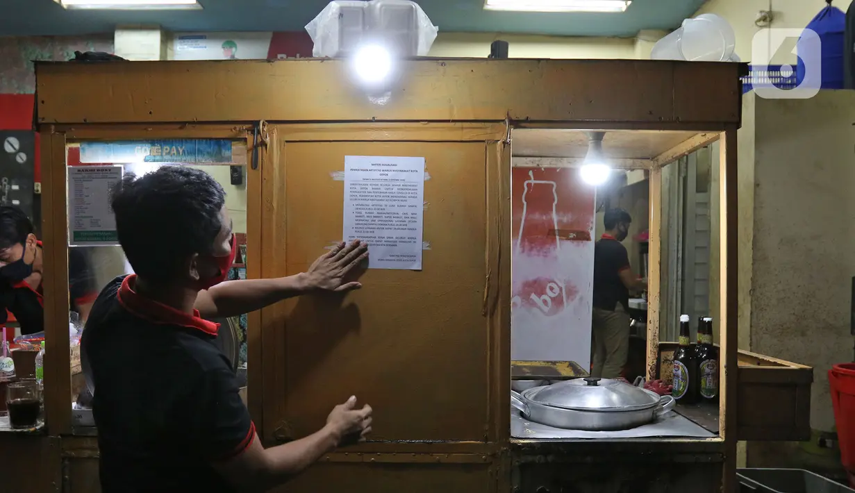 Pekerja menempelkan surat sosialisasi aturan jam malam di warungnya  kawasan Margonda, Depok, Senin (31/8/2020). Pemkot Depok, Jawa Barat, mulai menerapkan aturan jam malam yang membatasi kegiatan masyarakat di luar rumah untuk menekan risiko penularan Covid-19. (Liputan6.com/Herman Zakharia)
