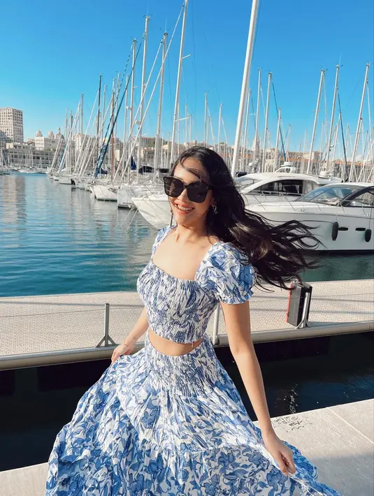 Set outfit berupa crop top dan tiered skirt motif bunga beri kesan manis sebagai outfit liburan. [Foto: IG/anyageraldine].