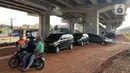 Warga berbincang dekat mobil yang parkir di kolong jalan tol Becakayu di kawasan Cipinang Muara, Jakarta, Jumat (13/3/2020). Minimnya lahan parkir membuat sebagian orang tetap memarkirkan kendaraannya di kolong tol tersebut, meskipun telah terpampang larangan parkir. (Liputan6.com/Immanuel Antonius)