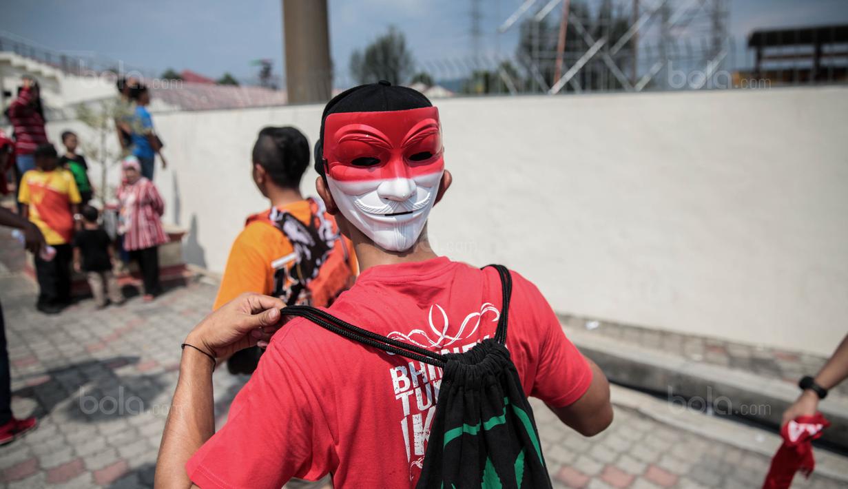 Seorang suporter Timnas Indonesia memakai topeng akan menonton pertandingan melawan Timor Leste pada laga SEA Games di Stadion MPS, Selangor, Minggu (20/8/2017). Indonesia menang 1-0 atas Timor Leste. (Liputan6/Faizal Fanani)