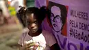 Seorang anak di depan spanduk bergambar Presiden Brasil terdahulu, Dilma Rousseff pada unjuk rasa di Rio de Janerio, Rabu (2/8). Pemungutan suara dilakukan untuk memutuskan apakah Presiden Michel Temer harus lengser atau tidak. (AP/Silvia Izquierdo)