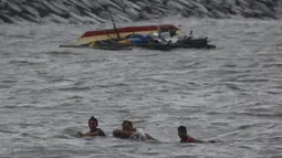 Tiga orang nelayan berusaha berenang ke darat setelah perahu mereka terbalik akibat Topan Nepartak yang menerpa Manila Bay, Filipina, Jumat (8/7). (REUTERS/Erik De Castro)