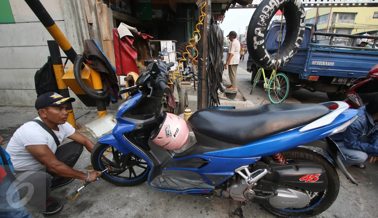 Seorang juru tambal usai memperbaiki motor pengendara yang terkena operasi cabut pentil,  Jakarta, Jumat (23/10/2015). Dengan tarif Rp3.000 para juru tambal mendapat banyak keuntungan. (Liputan6.com/Immanuel Antonius)