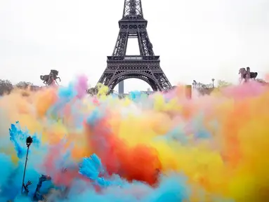Sejumlah orang melempar bubuk berwarna saat merayakan akhir perlombaan Color Run 2018 di depan Menara Eiffel di Paris, Prancis (15/4). Dengan acara ini sekitar Menara Eiffel terlihat berwarna-warni. (AP/Thibault Camus)