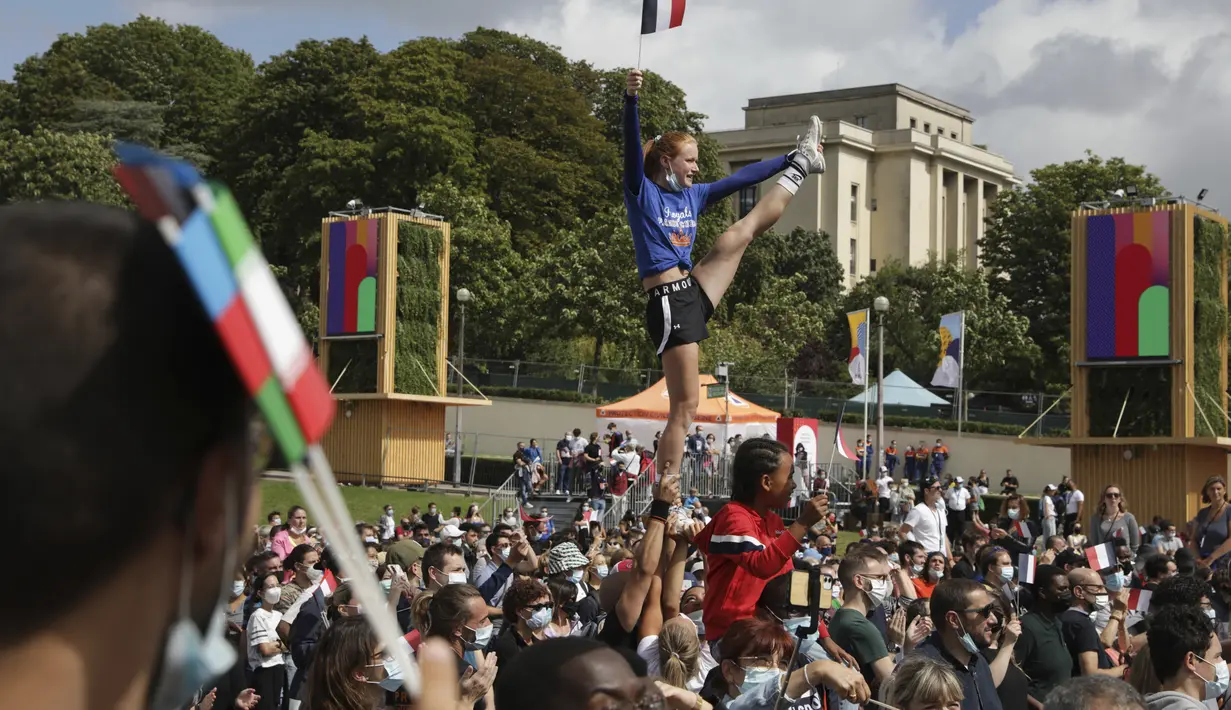 Seorang wanita memegang bendera Prancis saat dia melakukan akrobat di zona penggemar Olimpiade di Trocadero di Paris, Minggu (8/8/2021). Warga Paris pun antusias menyambut pagelaran pesta olahraga terbesar di dunia itu. (AP Photo/Francois Mori)