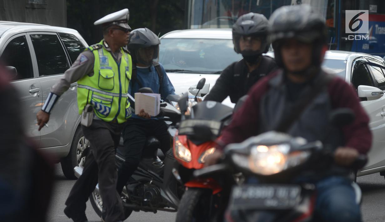Polantas memberhentikan pengendara motor saat Operasi Patuh Jaya 2018 di Jalan DI Panjaitan, Jakarta Timur, Jumat (27/4). Khusus untuk razia ini, para polantas akan memburu mereka yang menggunakan ponsel sambil berkendara. (Merdeka.com/Imam Buhori)
