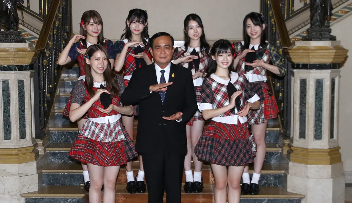 Grup musik Jepang, AKB48 berfoto bersama PM Thailand, Prayut Chan-O-Cha di Gedung Pemerintahan di Bangkok, Kamis (13/8). Kunjungan ini adalah promosi AKB48 untuk mempersiapkan konser di Bangkok pada Desember mendatang. (Government Spokesman Office via AP)