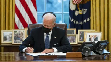 Presiden Amerika Serikat Joe Biden menandatangani Perintah Eksekutif yang membatalkan larangan bagi transgender untuk masuk militer AS pada era Donald Trump di Kantor Oval Gedung Putih, Washington, Senin (25/1/2021). (AP Photo/Evan Vucci)