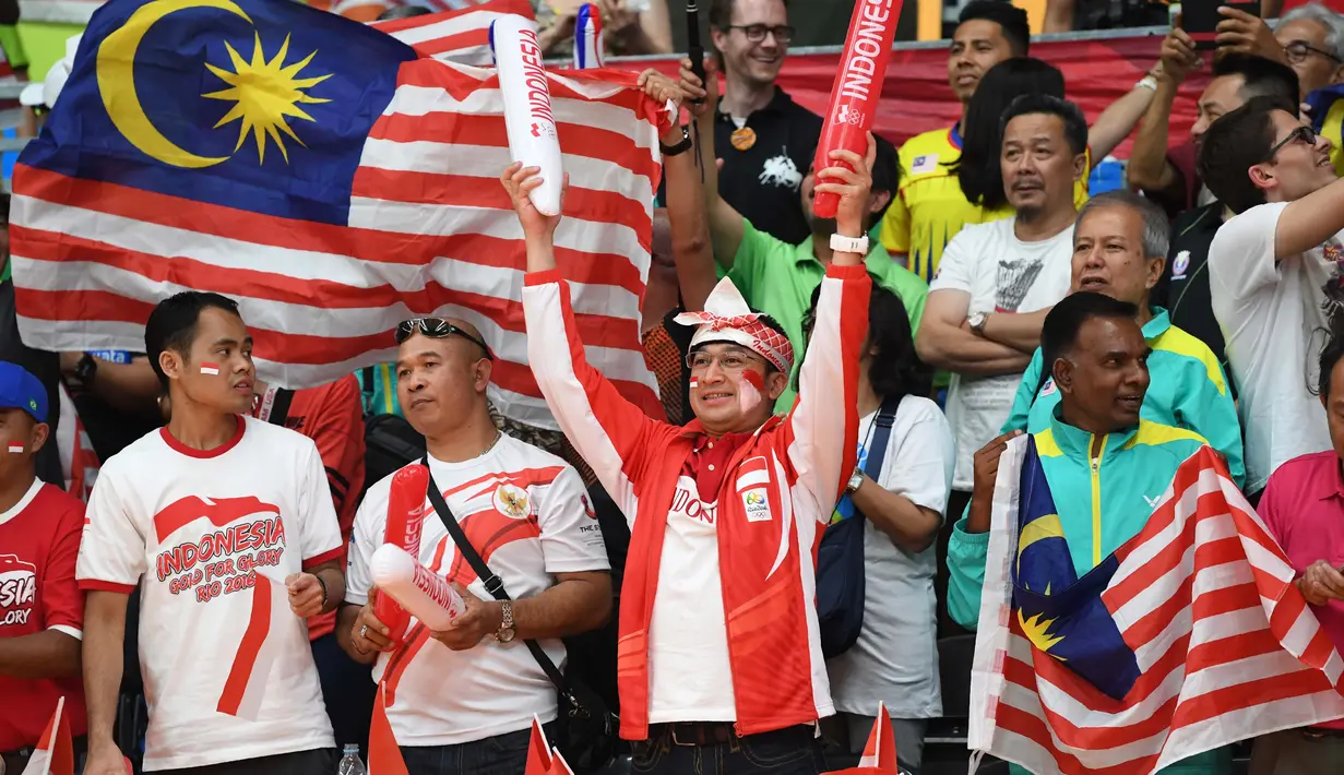 Suporter Indonesia dan Malaysia berdampingan memberi dukungan untuk jagoannya masing-masing saat final bulutangkis Olimpiade Rio 2016  di Stadion Riocentro, Rio de Janeiro, (17/8/2016). (AFP/Goh Chai Hin)