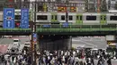 Orang-orang berjalan di sepanjang penyeberangan pejalan kaki di Tokyo, Selasa (22/6/2021). Ibu kota Jepang mengkonfirmasi lebih dari 430 kasus virus corona baru pada hari Selasa. (AP Photo/Eugene Hoshiko)